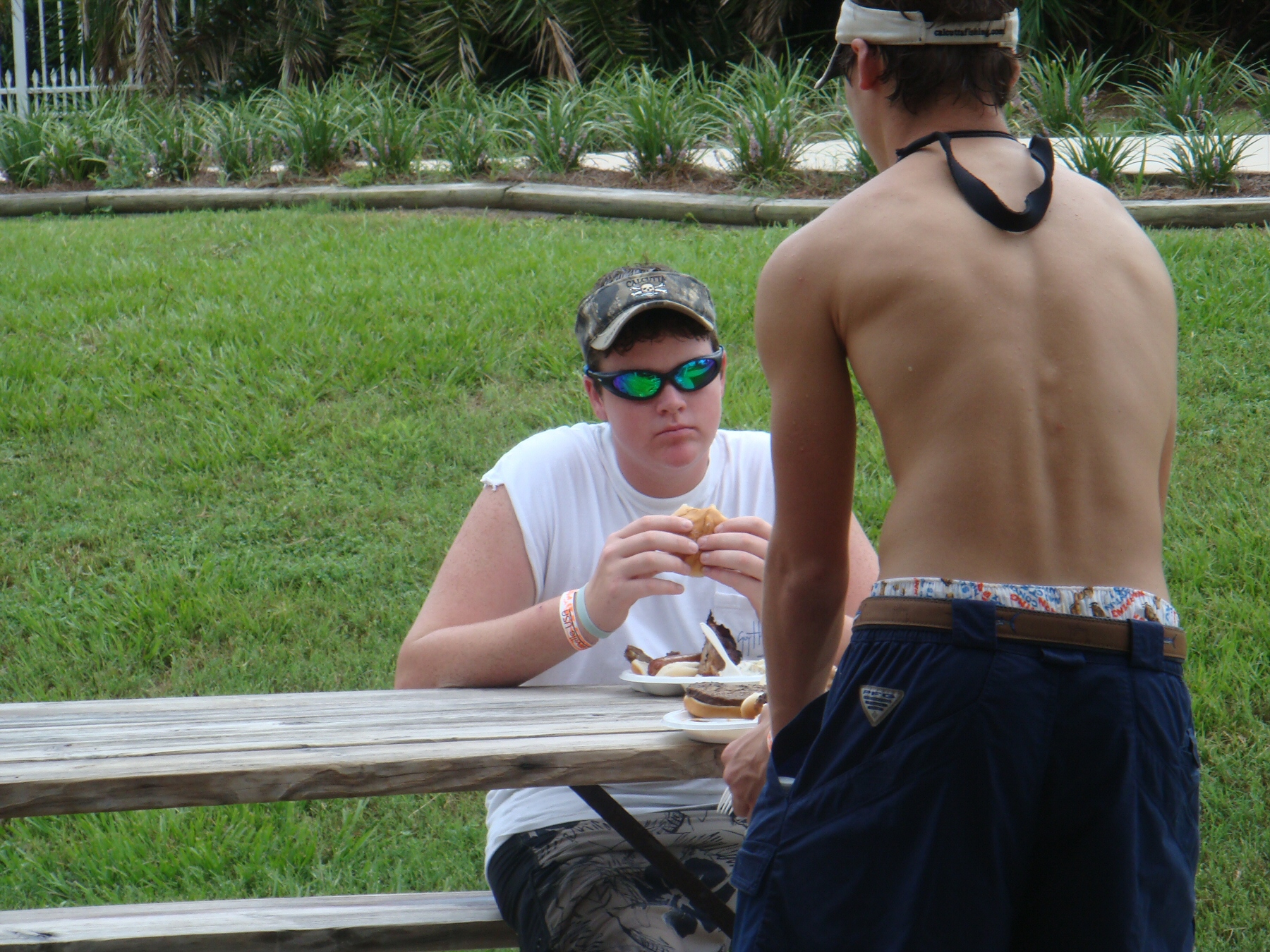 two men eating at picnic table