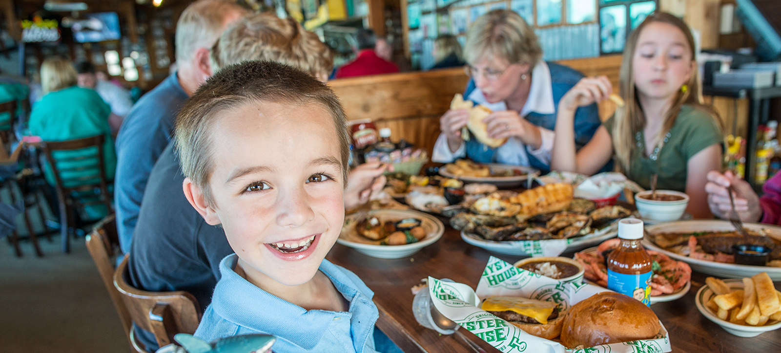Family eating seafood at Original Oyster House Restaurant with boy smiling